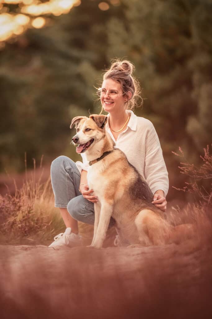 Glückliche Frau mit Hund im Freien bei Sonnenuntergang, Natur, Freude, Tierliebe.