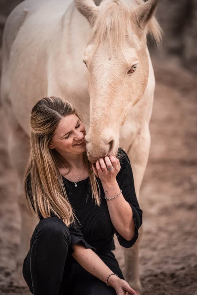 Alena Süßenbach mit einem weißen Pferd, zeigt eine liebevolle Verbindung und Naturfotografie.