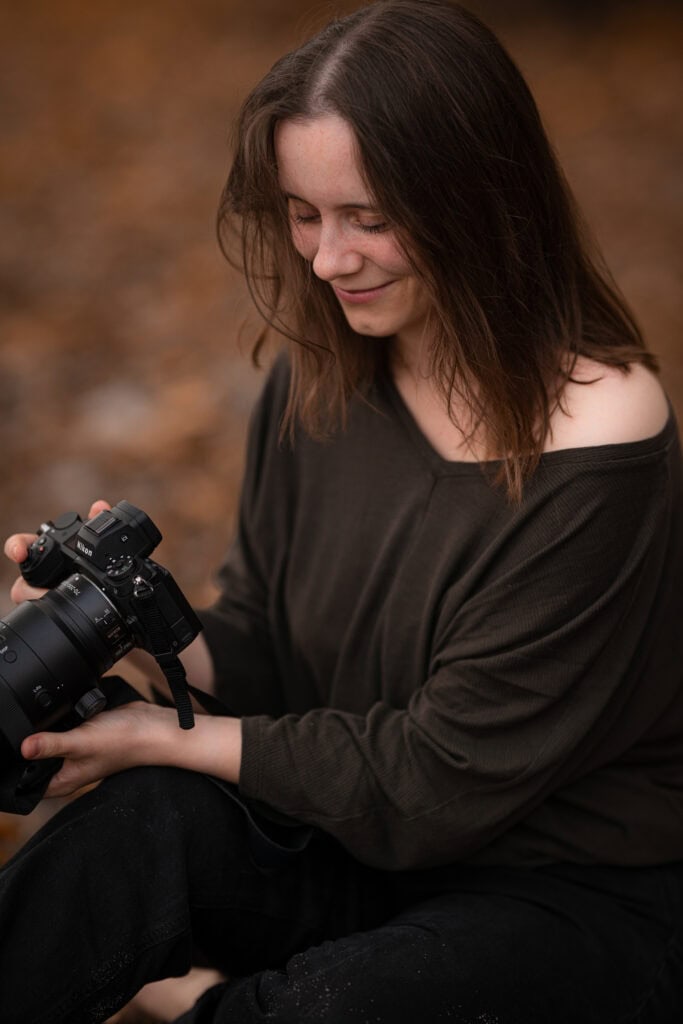 Alena Süßenbach hält eine Kamera, Naturfotografie, Herbstlandschaft.