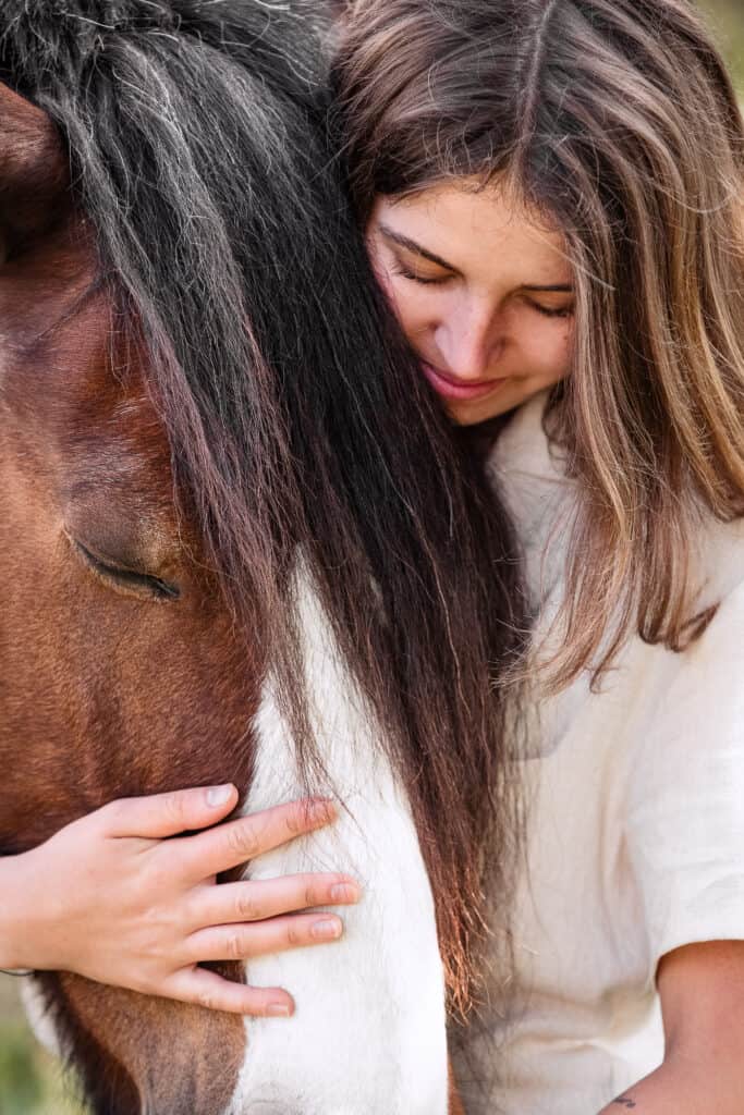 Junge Frau umarmt ein braunes Pferd, emotionale Verbindung, Naturfotografie.